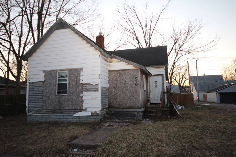 Abandoned house in disrepair with peeling paint and boarded-up windows at dusk